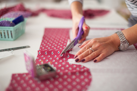 Tailor measuring textile material. young woman seamstress making pattern on fabric with tailors chalk. Girl working with a sewing pattern. Hobby sewing as a small business concept. Tailor measuring textile materialの写真素材