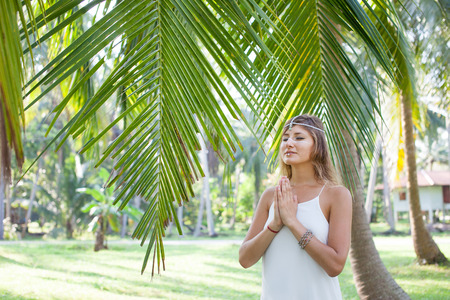 Phangan, Thailand. A beautiful young woman stands in a palm grove in the rays of the morning sun.の写真素材