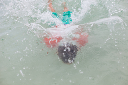 A young boy runs through the waterの写真素材