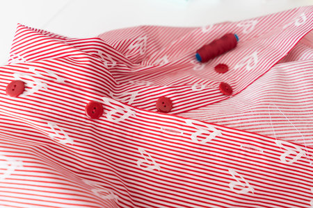 Striped fabric with hearts. The tailor's accessories lie on the fabric.
