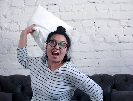 Girl with open mouth throws a pillowの写真素材