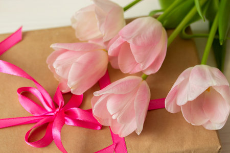 Bouquet of pink tulips on a gift box. Gift and flowers, bright pink ribbon, a bouquet of fresh spring flowers, close-upの写真素材