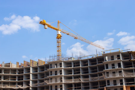 Yellow construction crane working on the construction of a multi-storey residential building. New...