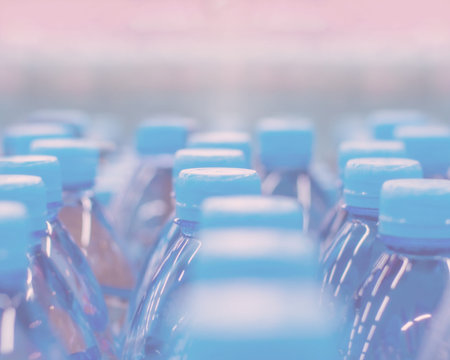 Defocus background, blue caps set bottled water. Pure drinking water in blue plastic bottles. Pink...