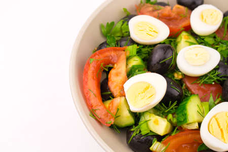 Mix of fresh vegetables Greek. Salad with quail eggs tomato cucumber olive. cut plate with egg and vegetable salad on whiteの写真素材