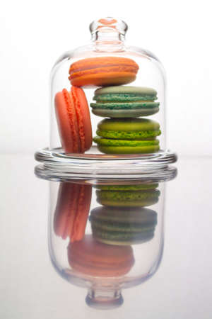 Macaroon cakes in a glass case. Multicolored french sponge cake dessert behind glass, vertical reflectionの写真素材