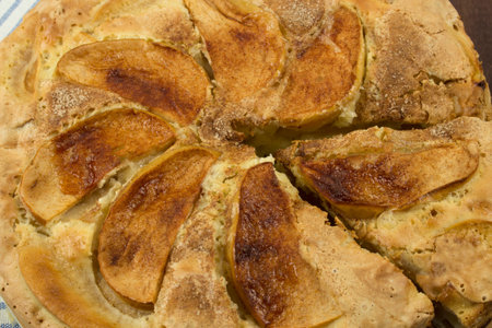 Close-up of apple pie with large slices of apples and a sliced piece, background, top view. Sweet...