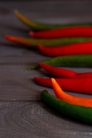 The sharp end of red hot chili peppers, tails of caen pepper on a dark wooden background, low key, spice food seasoningの写真素材