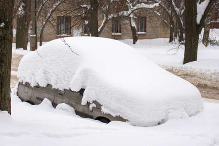 Passenger car completely hidden under a thick layer of snow. Winter, city street, car buried under a snowdrift. Personal gray transport stuck in the snowの写真素材