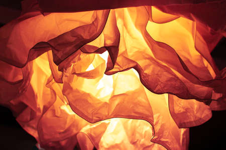 Abstract defocus background orange backdrop, crumpled paper lit by a lamp. Color of the Year 2020 Lava backdrop background wallpaper, photo tinted in trendy Lava orange colorの写真素材