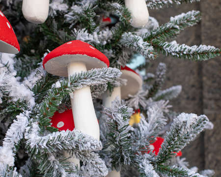 Artificial mushroom Amanita decorates a Christmas tree. Amanita with a red hat close-up. Snow-covered branches of an artificial Christmas treeの写真素材