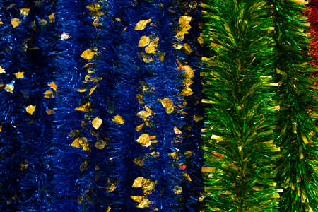 Foil blue green tinsel with golden leaves, backdrop close-up background. Stripes glittering garland of bright polythene foil, Christmas decoration, defocus bokeh background for designの写真素材