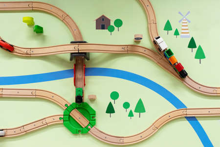 Children's wooden railway with a steam locomotive, top view. A painted landscape with a river, a toy railway with a crossing, a bridge and a road junction. Beautiful toy worldの写真素材