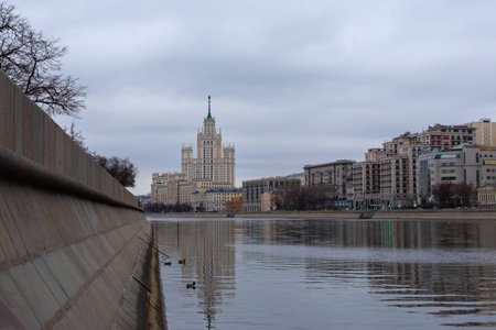 Moscow, Russia - January 7, 2020: Old Stalin skyscraper on the Kotelnicheskaya embankment of the Moscow River. Granite support of the embankment, smooth surface of the water.の写真素材