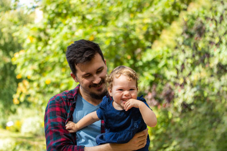 Laughing curly girl on a walk with dad. Young Caucasian European man with daughter outdoor