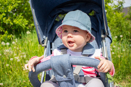 Smiling baby girl 9 months in panama walks in a stroller. A child in a good mood portrait close-up....