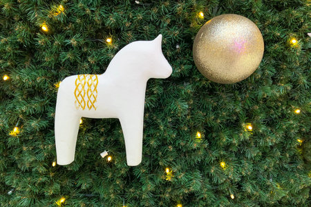 White wooden horse and golden decorative ball on the Christmas tree. Festive christmas background backdrop, christmas decoration. Simplicity and eco-friendly, artificial spruce Christmas treeの写真素材