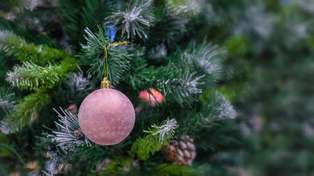 Christmas tree with a delicate pink ball with snowflakes. Festive Christmas blurred background design. Winter seasonal holiday, christmas decoration, ball in hoarfrostの写真素材