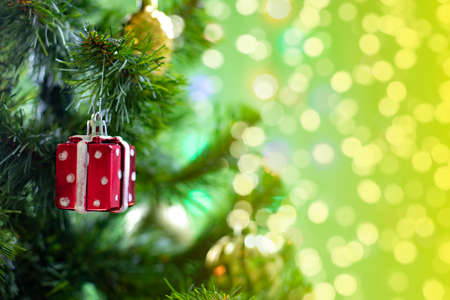 Christmas decoration red box with a gift hanging on a branch of a christmas tree, sparkling shiny background copy space design for a postcard or leafletの写真素材