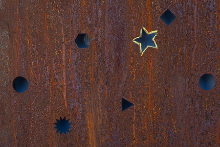 Old rusty metal sheet with cuts in the shape of a circle and a star and traces of corrosion and rust, texture backgroundの写真素材