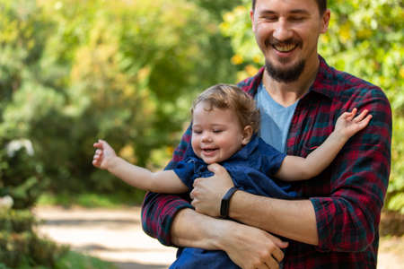 Dad and daughter laughing happy faces, family play in nature. Young father holding baby girl and smilingの写真素材