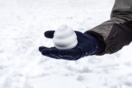 Snowball in the form of a cake on a hand in a mitten, winter outdoor games. Season mood snowy weatherの写真素材