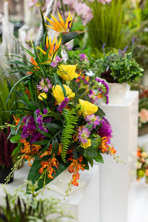 Floral interior decor, artificial bouquet of flowers yellow rose green fern on a white pedestal vertical photographyの写真素材