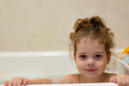Little caucasian girl in the bathroom bathing the baby in the home bath