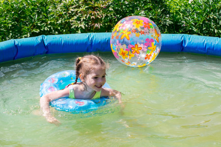Caucasian girl swimming in the pool outdoors, child 4 years old playing in the backyard, horizontal photographyの写真素材