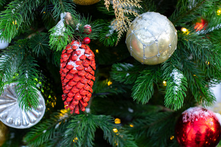 Red cone Christmas toy on a spruce branch covered with snow close-up, festive New Year card backgroundの写真素材