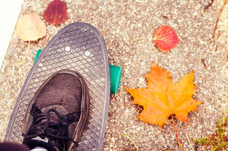 Riding a cruiser in autumn. Skateboarding outdoors at fall time.の写真素材