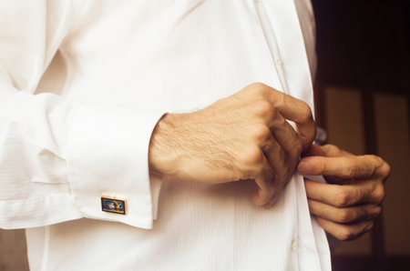 Man buttoning his shirt for a special occasion