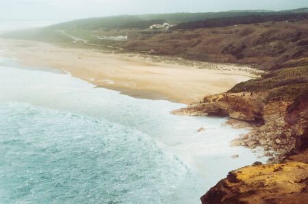 A beautiful scenery with white waterduring big swell at coastline of Nazare, Portugalの写真素材