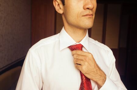 Man fixing a red tie in the morning preparing for a serious business meetingの写真素材