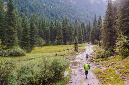 Small figures of people on a trail surrounded by a majestic mountain sceneryの写真素材