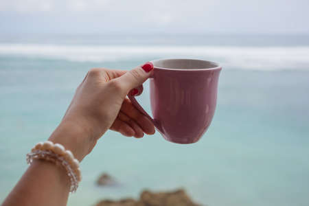 Good morning. Girl holding mug against ocean viewの写真素材