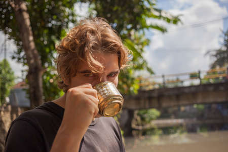 Man drink coffee from golden cup at summer picnicの写真素材