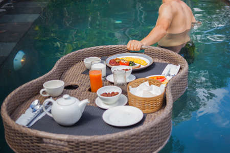 anonymous male traveler holding food tray on waterの写真素材