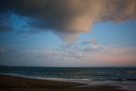 Beautiful dramatic sunrise with cloudy dark sky and green ocean waves. Moody seascape. Natural background of seaside and sea comb Film grain texture. Soft focus. Blur. Copy space.の写真素材