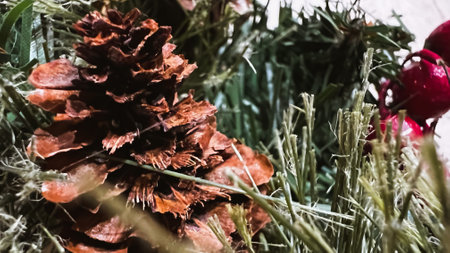 Macro pine tree cone among needles of fir tree and red berries. Close-up Christmas wreathe. Xmas festive decor. Soft focus. film grain pixel texture. Defocused.の写真素材