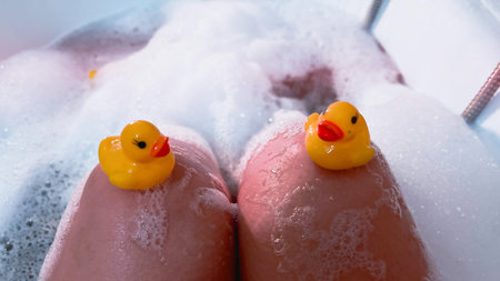 POV bathing in bath foam with cute yellow rubber ducks. Adult playing while taking bath at home....