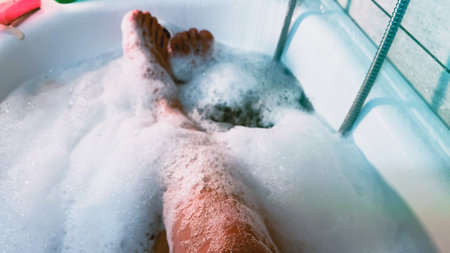 POV person lying in a bath tub filled with water and soap bubble foam. Take bubble bath for relaxation. Lying in bath bubbles. Fun time at home. Soft focus. film grain pixel texture. Defocused.の写真素材