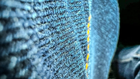 Close-up macro view of blue jeans. Pants from denim with yellow stitches. ZClassical American jeans. Soft focus. film grain pixel texture. Defocused.の写真素材