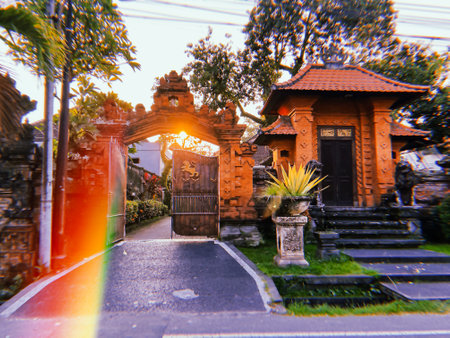 Balinese temple at sunrise with rainbow lens flare. Bali island religion. Hindu gate. Travel Indonesia. Film grain texture. Soft focus. Blurの写真素材