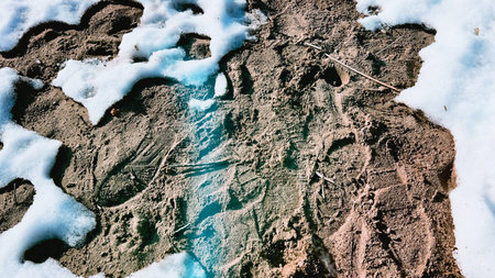 Wallpaper with sand under snow. Winter beach. Vintage style background with sandy surface and foot...