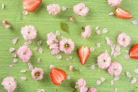 Colorful summer or spring nature background. Pink almond flowers, bud, leaf and petal on green wooden natural background, flat lay. Top viewの写真素材