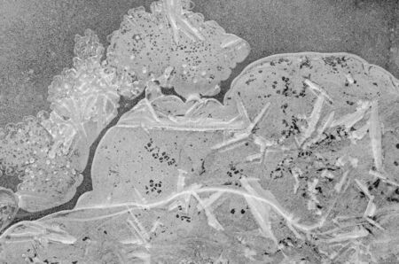 Winter frozen ice water structure of white transparent ice background, seasonal texture of frozen water on the river, black and white photographyの写真素材