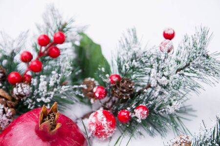 Beautiful Christmas background with pomegranate fruit and fir branches on snow, winter seasonの写真素材