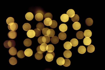 Yellow bokeh circles defocused on a dark blurred background. Texture for Christmas holiday designの写真素材