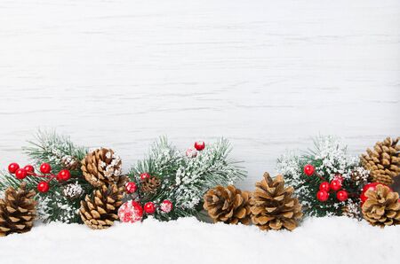 Christmas snow scene. Christmas tree branches with cones and ornaments on  wooden light background,  copy  spaceの写真素材